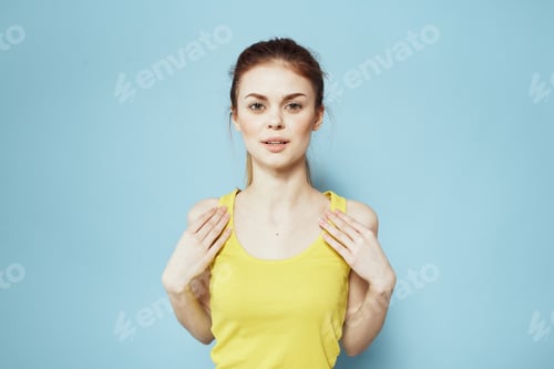 Vista previa: Sportive woman yellow tank top pigtail towards fitness blue background