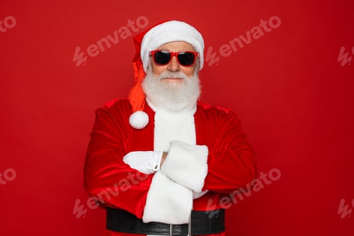 Preview: Confident Santa Claus in sunglasses arms crossed folded looking at camera isolated red background