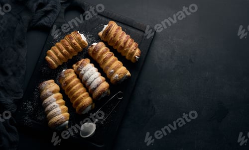 Preview: baked tubules filled with whipped egg white cream on a black wooden kitchen board, top view