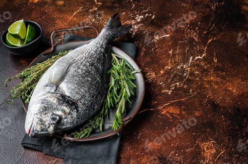Preview: Uncooked Raw sea bream or dorado fish with herbs. Dark background. Top view. Copy space
