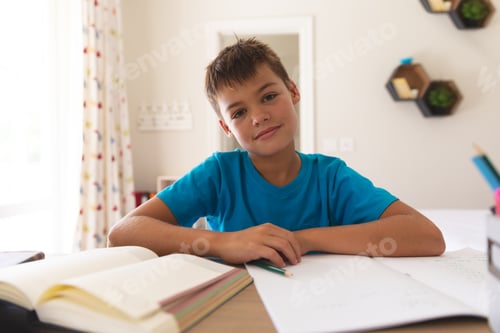 Preview: Smiling caucasian boy having video call during class, sitting at desk at home