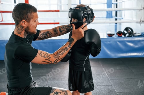 Preview: In protective helmet. Coach is teaching the boy box techniques indoors