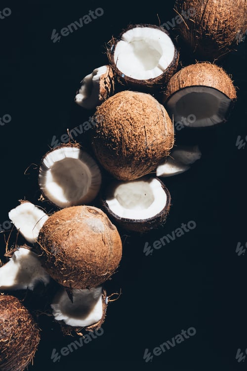 Preview: top view of whole and cracked organic coconuts isolated on black