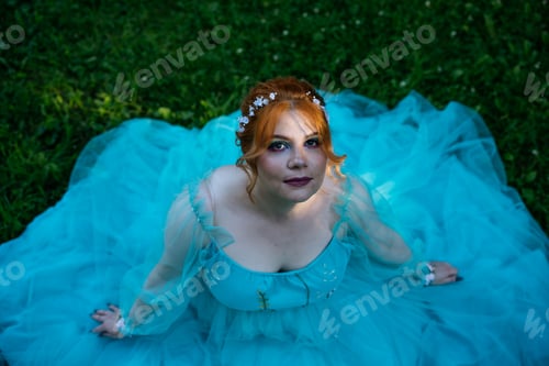 Preview: Top view of redhead young bride with acne in blue dress in park. Wedding or prom photo.