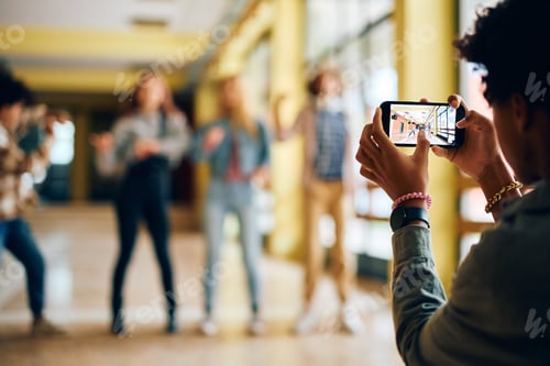 Preview: Close up of high school student taking picture of his friends with smart phone.