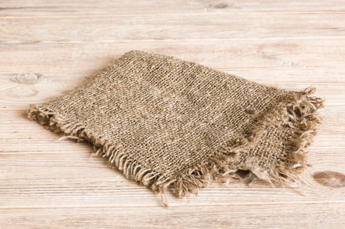 Preview: Old burlap fabric napkin, sackcloth on table background. top view with copy space