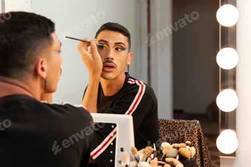 Preview: young man in front of the mirror making up drag queen artist