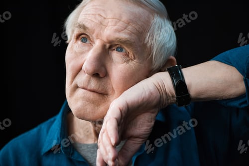 Preview: portrait of senior man listening to watch on wrist isolated on black