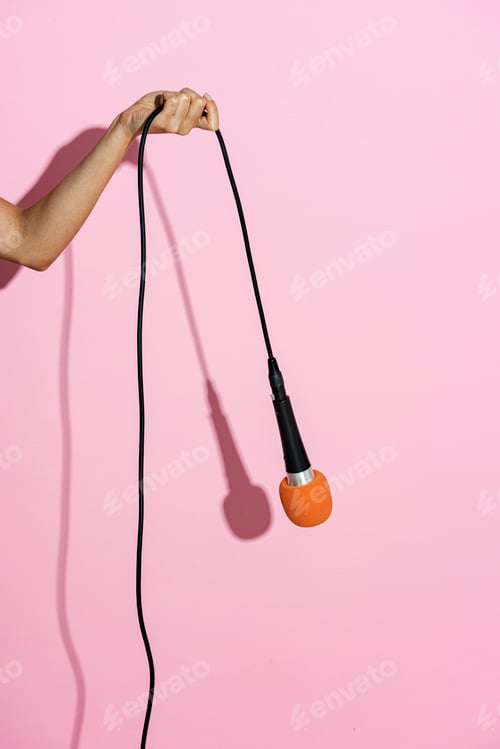 Preview: Hand holding a microphone on pink background
