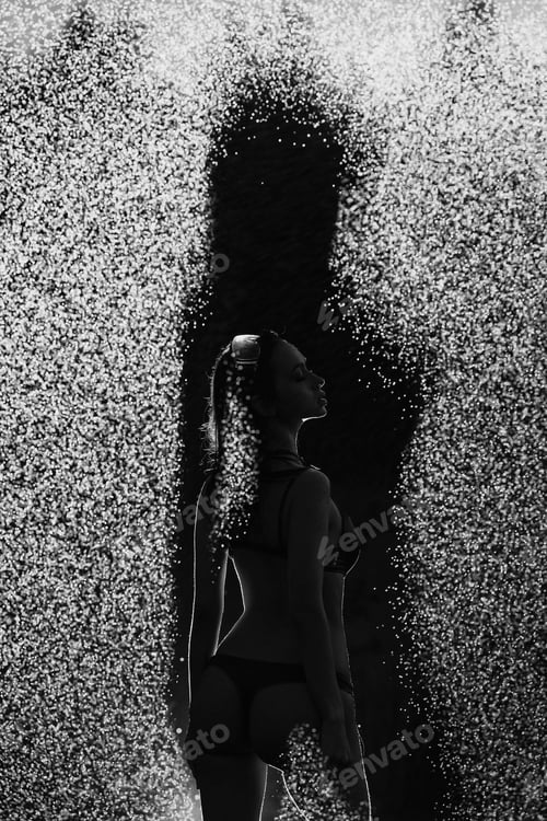 Preview: A woman stands in the rain, her body partially obscured by the spray of water