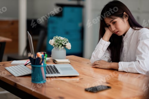 Preview: Bored asian female worker lie at office desk look at mobile phone and laptop screen think about