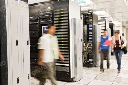 Preview: Three multi-ethnic technicians working in a large computer server room.