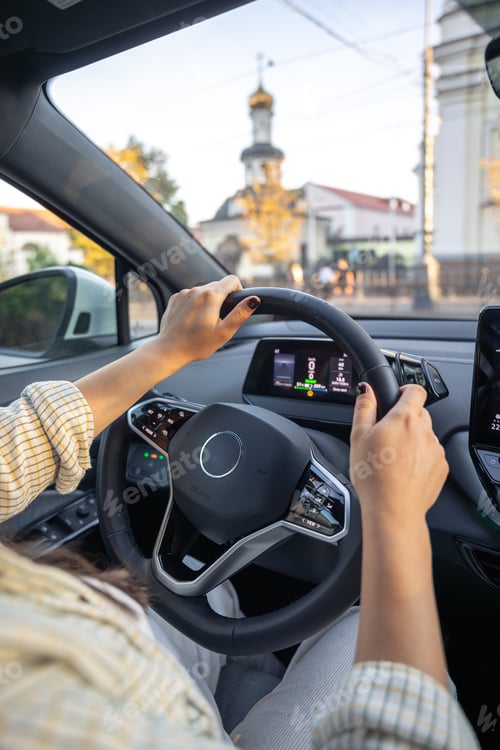 Preview: Young woman driving a car. Hands on the wheel. View from the back to the road.