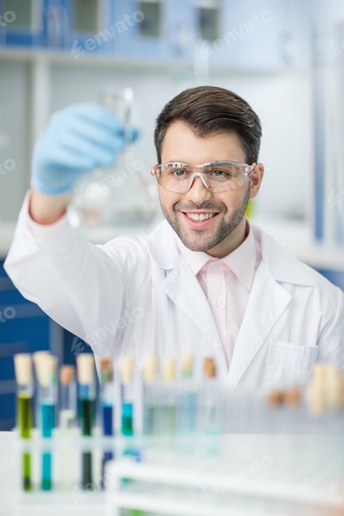 Preview: portrait of smiling scientist in protective glasses holding glass tube
