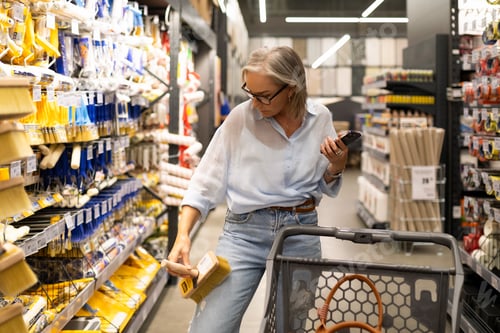 Preview: Woman shopping for paint supplies in a home improvement store aisle during midday