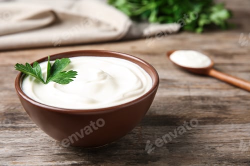 Preview: Bowl of fresh sour cream with parsley on wooden table