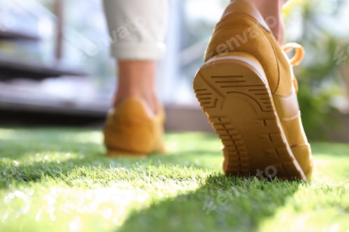 Preview: Young woman wearing stylish sneakers on green grass, closeup
