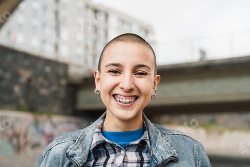 Preview: Happy young woman with shaved head smiling in front of camera