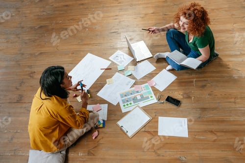 Preview: Two young women discussing new project sitting on the floor