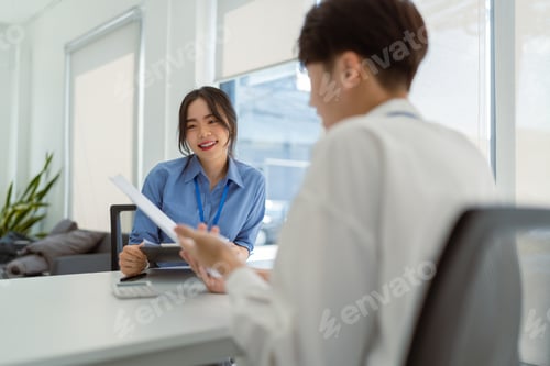 Preview: Two Asian colleagues discussing work Businessman holding a tablet in the office