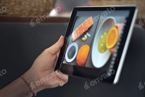 Preview: man hand using digital tablet watching online cooking master class. learning cooking remotely