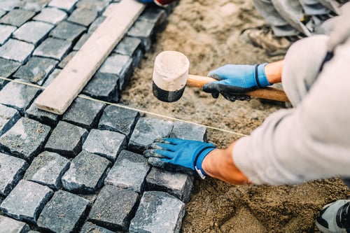 Preview: Construction worker installing stone on pavement. Details of construction site