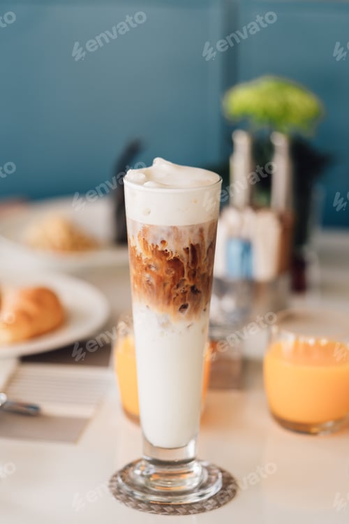 Preview: Iced cappuccino coffee in a tall glass cup on table with breakfast background