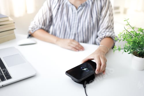 Preview: Charging mobile phone battery with wireless charging device in the table.