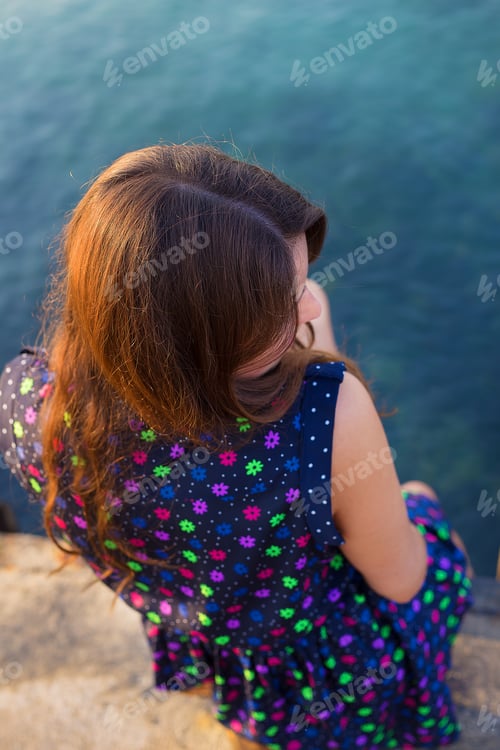 Preview: The girl in a beautiful dress is sitting on the pier.