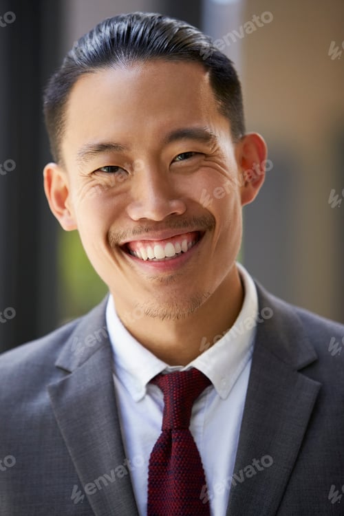 Preview: Young Asian businessman smiles to camera, close up, vertical