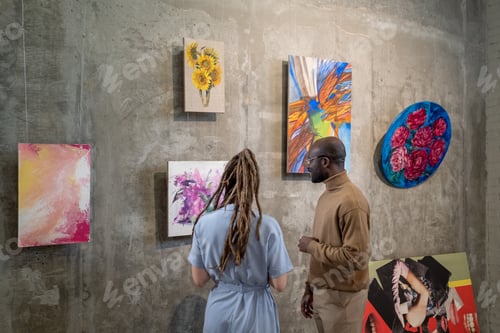 Preview: Young intercultural man and woman discussing one of paintings