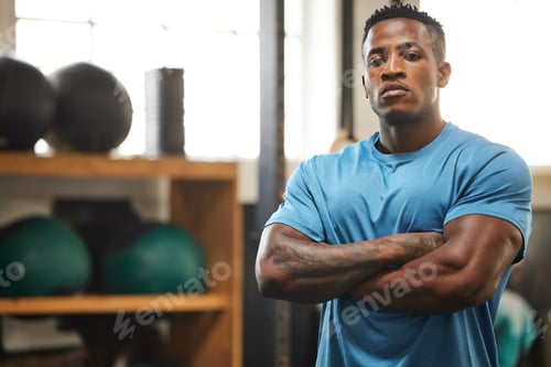 Preview: Portrait of a muscular young man standing with his arms crossed in a gym