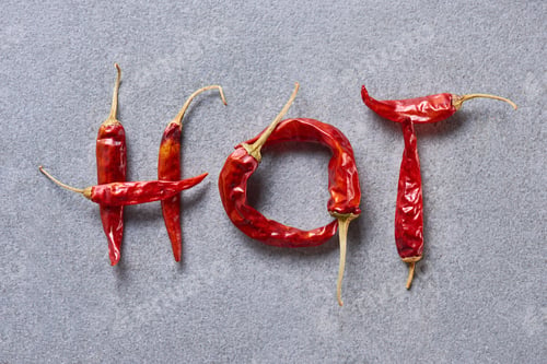 Preview: top view of chili peppers arranged in hot lettering on grey tabletop