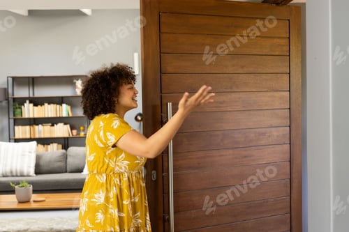 Preview: Welcoming guests, African American woman greeting at home with joyful expression