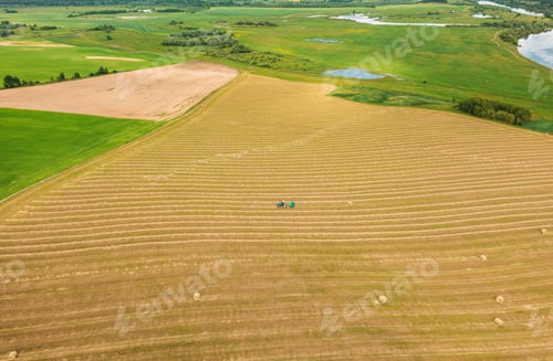 Preview: Aerial View Tractor Collects Dry Grass In Straw Bales In Wheat Field. Special Agricultural Equipment