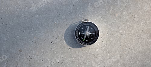 Preview: Round stylish compass on concrete background, search direction in summer mountains, point of view.