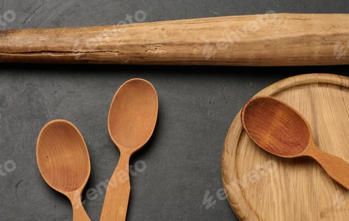 Preview: Wooden spoons, cutting board and rolling pin on a dark surface