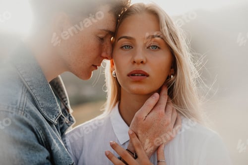 Preview: Young couple on a walk in nature at sunset in countryside, hugging