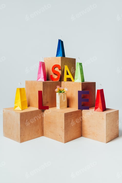 Preview: bright shopping bags on wooden stands with sale sign, summer sale concept