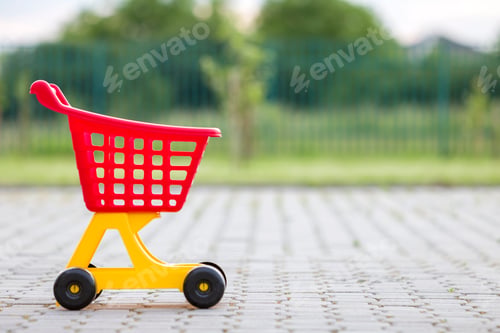 Preview: Bright plastic colorful shopping cart toy outdoors on sunny summer day.