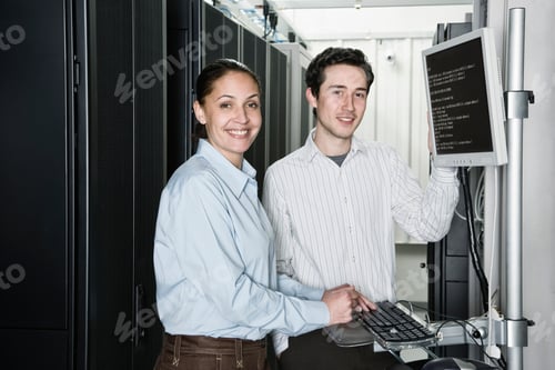 Preview: Caucasian man and woman computer techniciians checking data on computer servers in a computer