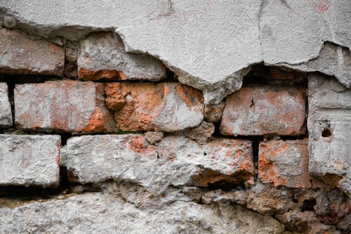 Preview: A red brick wall partially covered with crumbling plaster as an abstract, textural background.