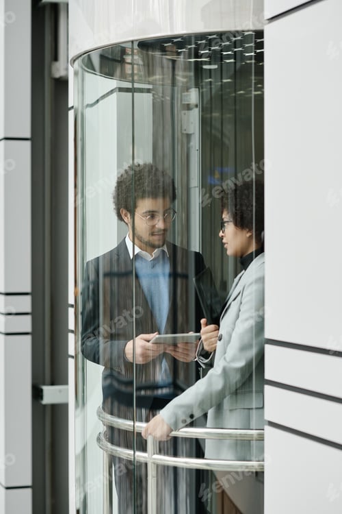 Preview: Business couple using tablet pc in elevator