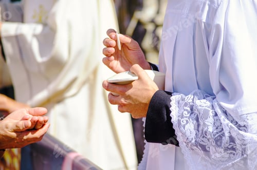 Preview: a catholic priest administering the sacrament of communion to attendees of an outdoor service
