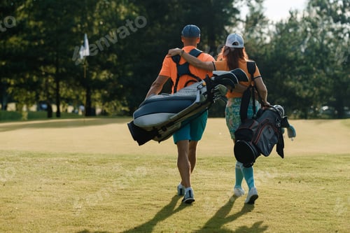 Preview: Couple enjoying a sunny day on the golf course while carrying their golf clubs together