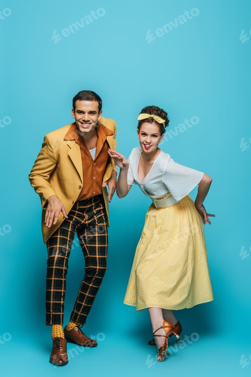 Preview: cheerful dancers looking at camera while dancing boogie-woogie on blue background