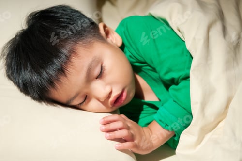 Preview: Close-up portrait of a young boy sleeping soundly in bed.
