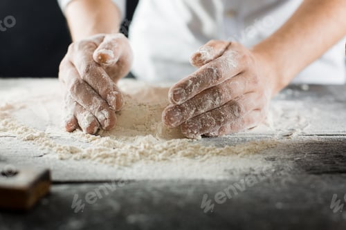 Preview: Male chef hands knead the dough with flour on the kitchen table