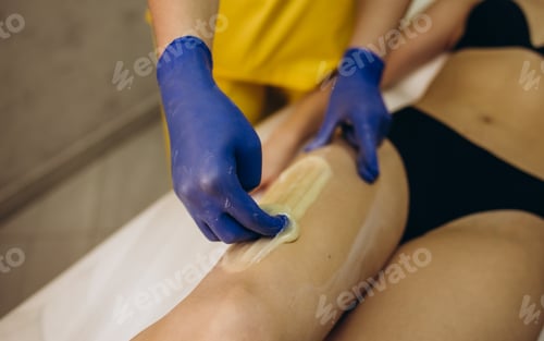 Preview: Beautician Waxing Leg Of Woman With Wax Strip At Beauty Clinic