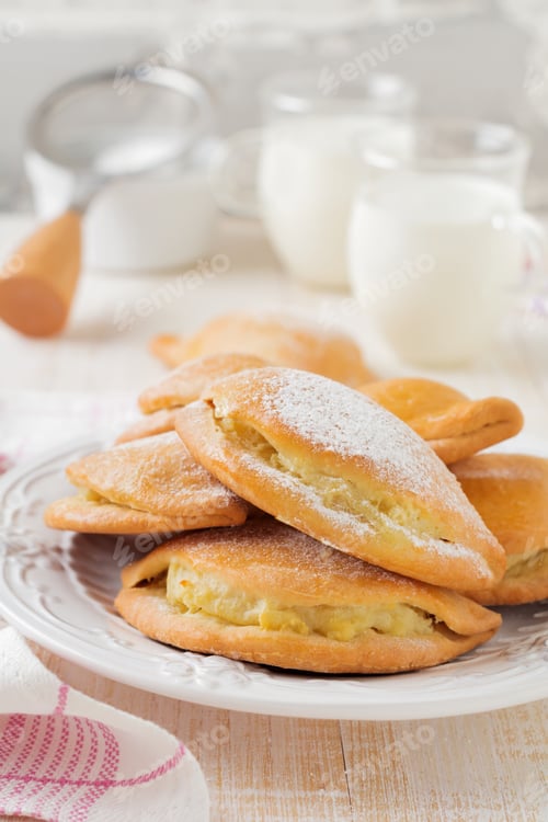 Preview: Pasties with cottage cheese and powdered sugar on a light wooden background. Traditional Russian pas